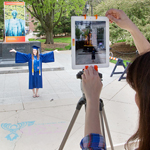 The augmented reality Alma Mater mobile app offered students many now-you-see-it, now-you-don't moments. Here, history and communication graduate Madeline Ley poses in front of the pedestal with a poster of Alma, which triggered the mobile app to insert a 3-D image of the Alma Mater sculpture.