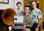 Chris Prom, assistant university archivist and professor of library administration, holds a laptop running the ARCHON software program. Prom developed the program with Scott Schwartz right, director of the Sousa Archives and Center for American Music and archivist for music and fine arts at Illinois, and undergraduate Kyle Fox, lead developer, who are standing next to a Victrola, part of the collection of the Sousa Archives and Center for American Music.