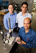 Taher Saif, a professor of mechanical science and engineering, holds a piezo actuated stage for nanoscale material studies in scanning electron microscopes. Graduate students Jong Han, left, and Jagannathan Rajagopalan explored aluminum films and gold films.