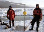 Paul A. Cziko, left) and Kevin Hoefling, a scientific research diver, prepare to place an oceanic current meter (yellow ball) and its home-made stand into the water. The 250-pound equipment is dropped off the edge of the ice floe to rest on the sea floor. A current meter allows scientists to obtain information on the velocity of seawater at a single location.