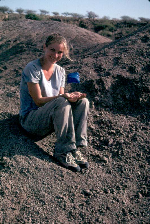 Leslea Hlusko, professor of anthropology, holds the fossil toe bone that she uncovered where the blue flag is in the ground near her in Ethiopia. The toe bone was among several fossils belonging to the earliest known human ancestor.