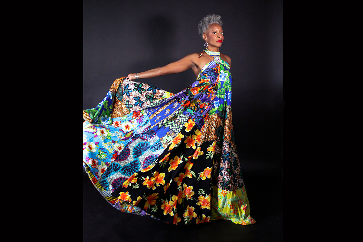 Dance professor Cynthia Oliver holding out the skirt of her colorful, full-length dress.