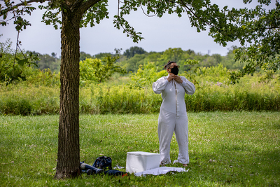 Vector ecologist Holly Tuten stands under a tree and buttons up her white coveralls.