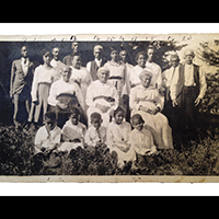 Black and white photo of a group of African American people outdoors, posed for a portrait and most of them wearing white.