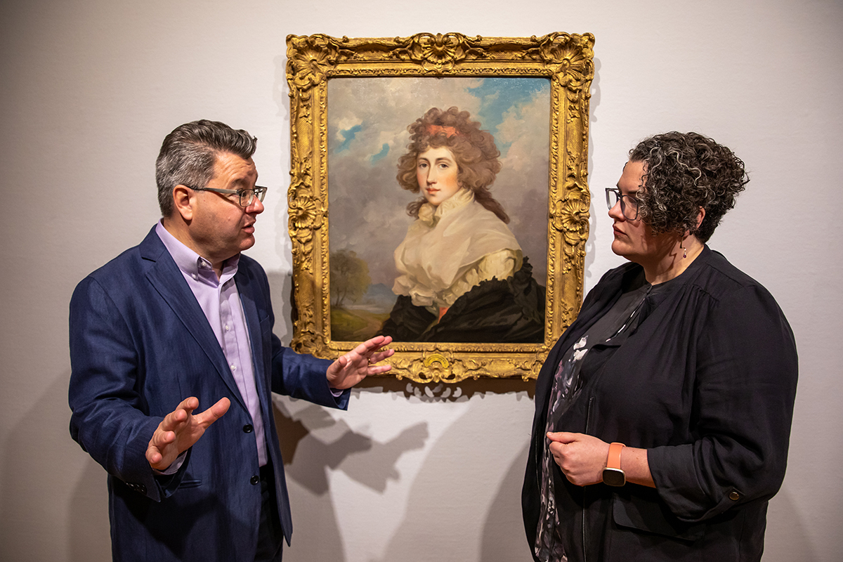 Photo of Craig Koslofsky and Maureen Warren talking in front of a portrait by John Hoppner in a Krannert Art Museum gallery.