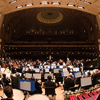 Wide-angle photo of the St. Louis Symphony Orchestra in a theater, taken from the back of the stage and looking toward the conductor.