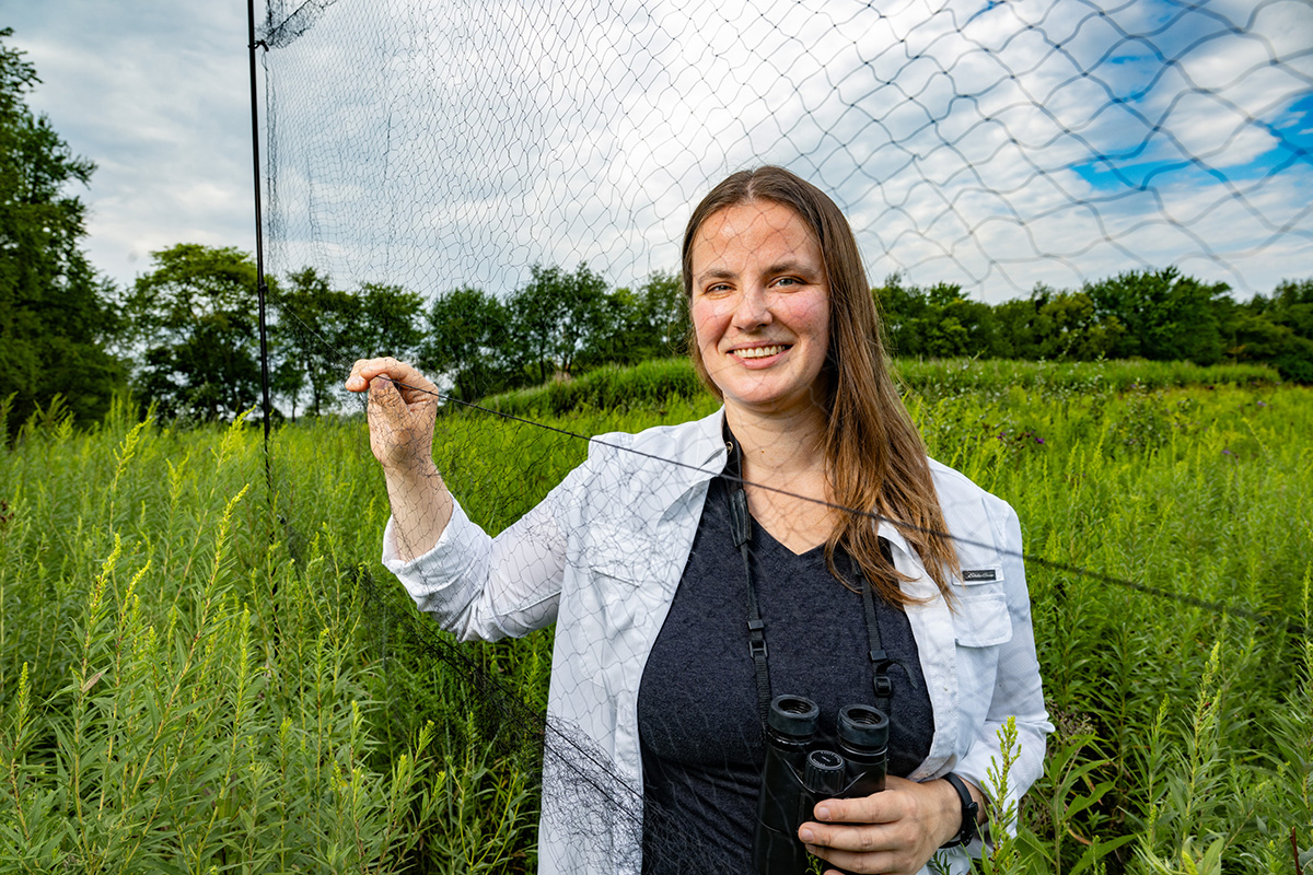 Photo of the researcher standing behind a mist net for capturing birds.