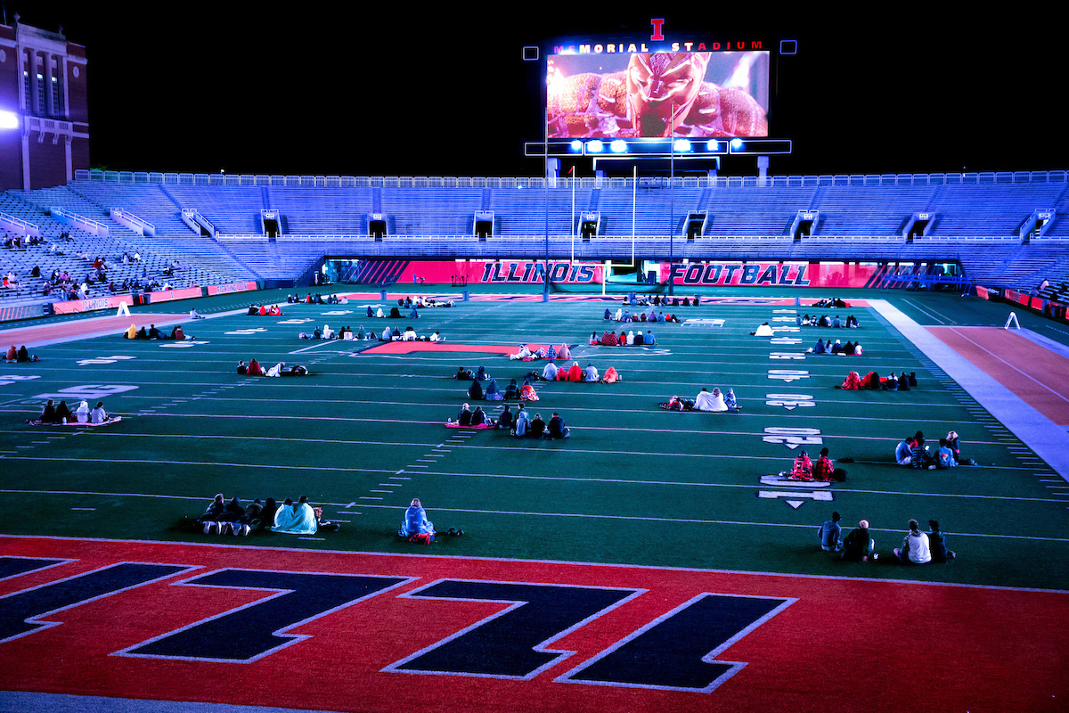 University of Illinois Urbana-Champaign students seated on the field of Memorial Stadium in social-distanced groups.