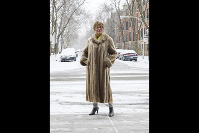 Photo of Gloria Allen standing in a full-length fur coat on a snowy street.