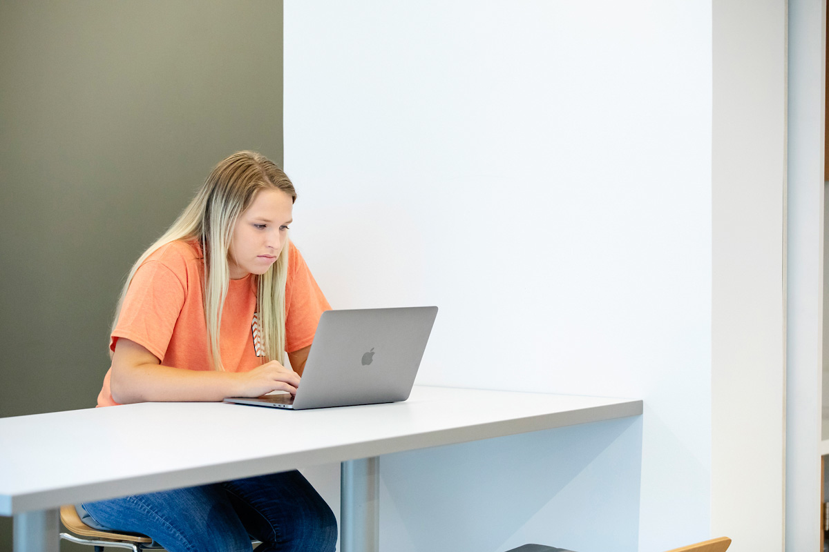 Female undergraduate student sitting at a table using a laptop computer