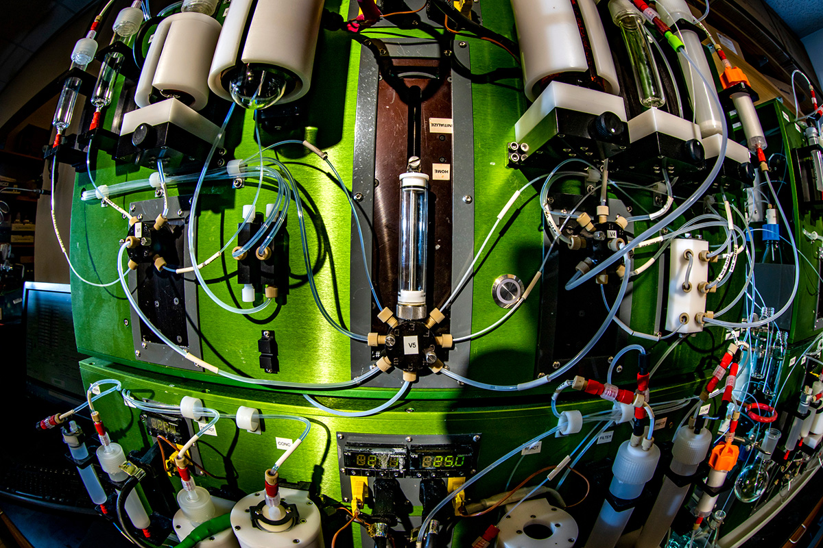 Photo of the molecule machine, a contraption with a lot of wires and tubular structures mounted on a bright green chassis.