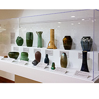 Photo of a display case featuring examples of Arts and Crafts pottery.