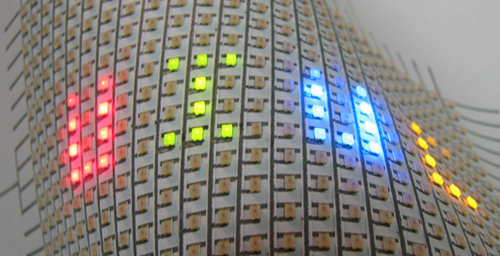 A flexible array of LEDs mounted on paper. Hand-drawn silver ink lines form the interconnects between the LEDs.