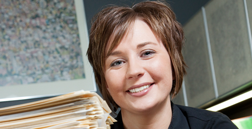 Jaclyn Banister, office administrator in Public Affairs, is shown next to a stack of Freedom of Information Act forms received by the campus. Changes to the Illinois FOIA that went into effect Jan. 1 reduced the amount of time that FOIA officers have to respond to most records requests and limit what public bodies such as the UI can charge for records.