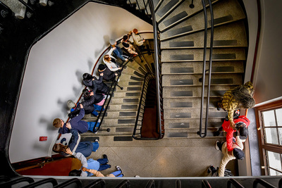 Photo shot from overhead of a line of people walking down a circular staircase.
