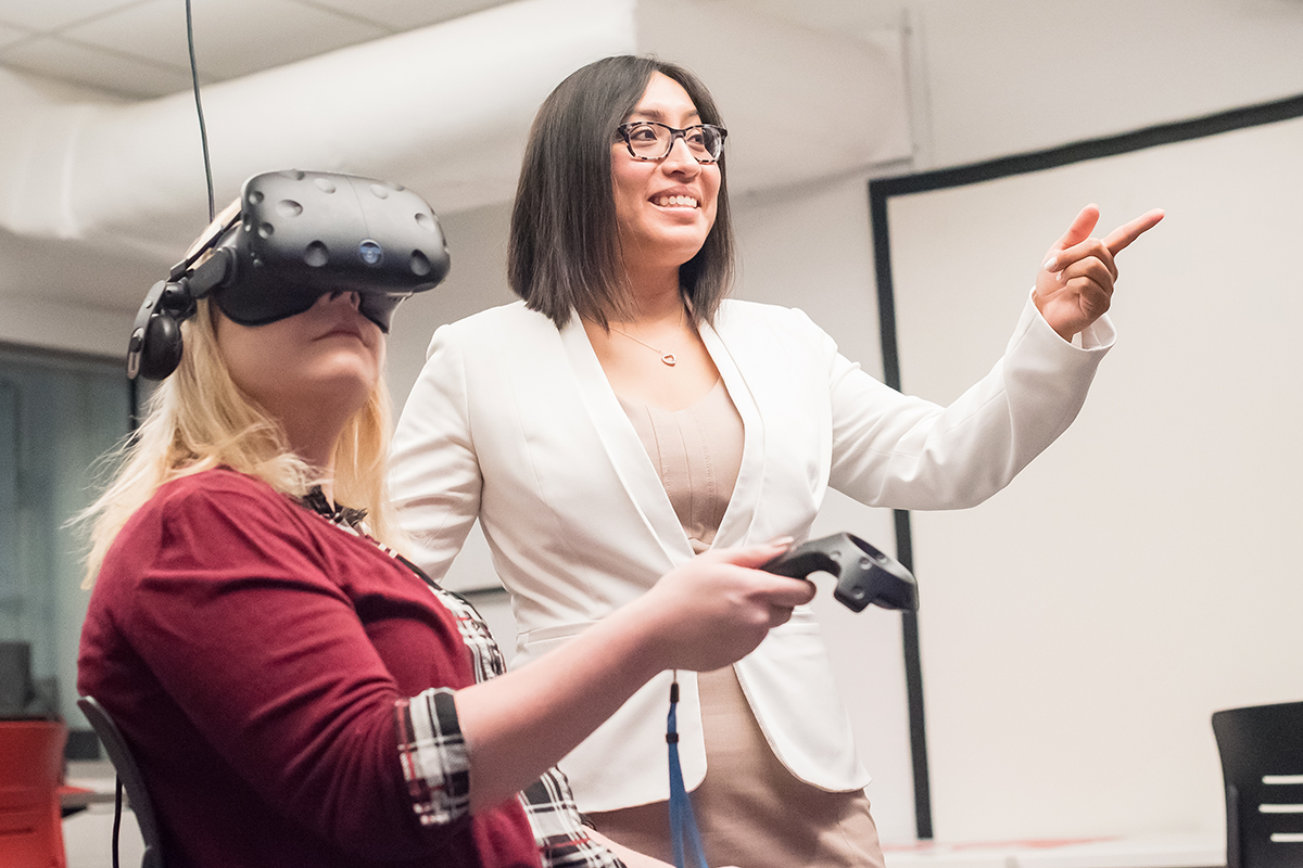 Professor Rosalba Hernandez assists visual media designer Drew Fast in using a virtual reality headset as part of their research into using the technology to help kidney dialysis patients ameliorate the physical effects and tedium of their dialysis treatments.