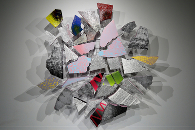 Image of artwork featuring fragments of debris that are painted and fastened to an armature in a circle.