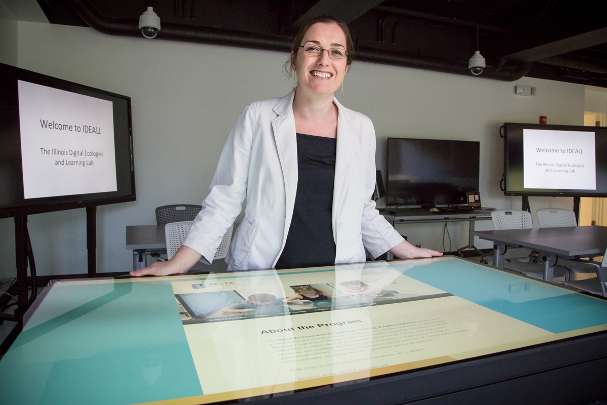 Emma Mercier is shown with tabletop and multiposition screens that she uses for interdisciplinary research projects with faculty members in engineering that focus on developing students collaborative problem-solving skills. Mercier is a professor of curriculum and instruction in education.