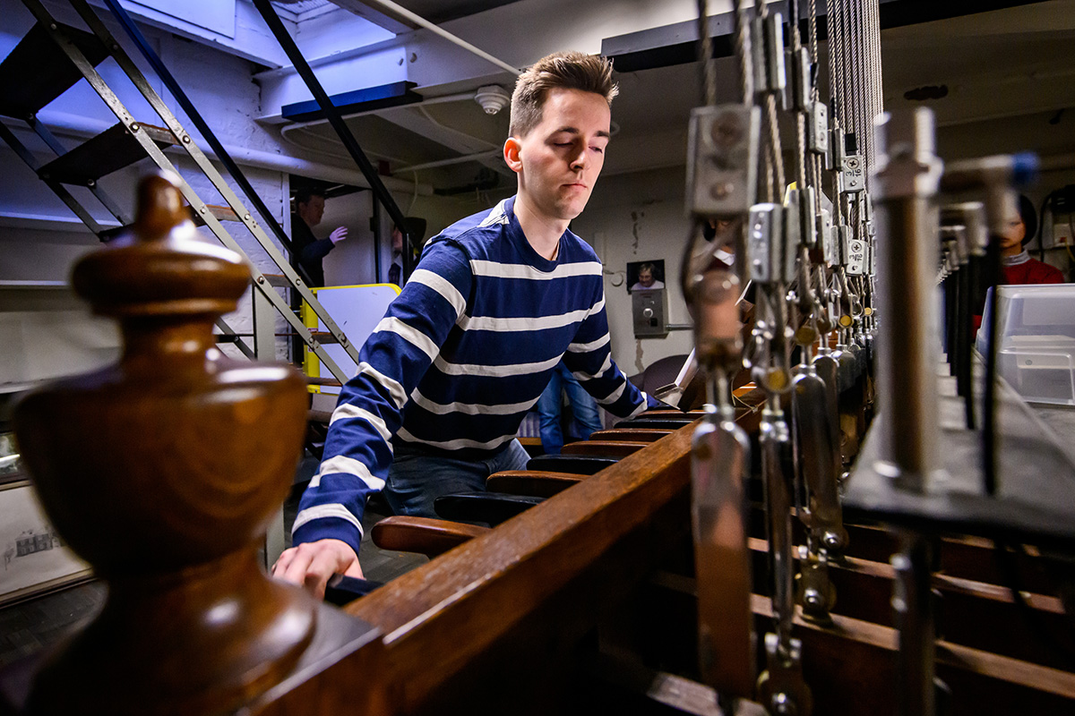 Photo of a chimes player reaching across the levers of the keyboard to play.