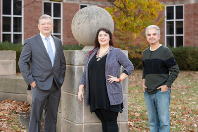 Three researchers appear to pose together outside on the university campus.
