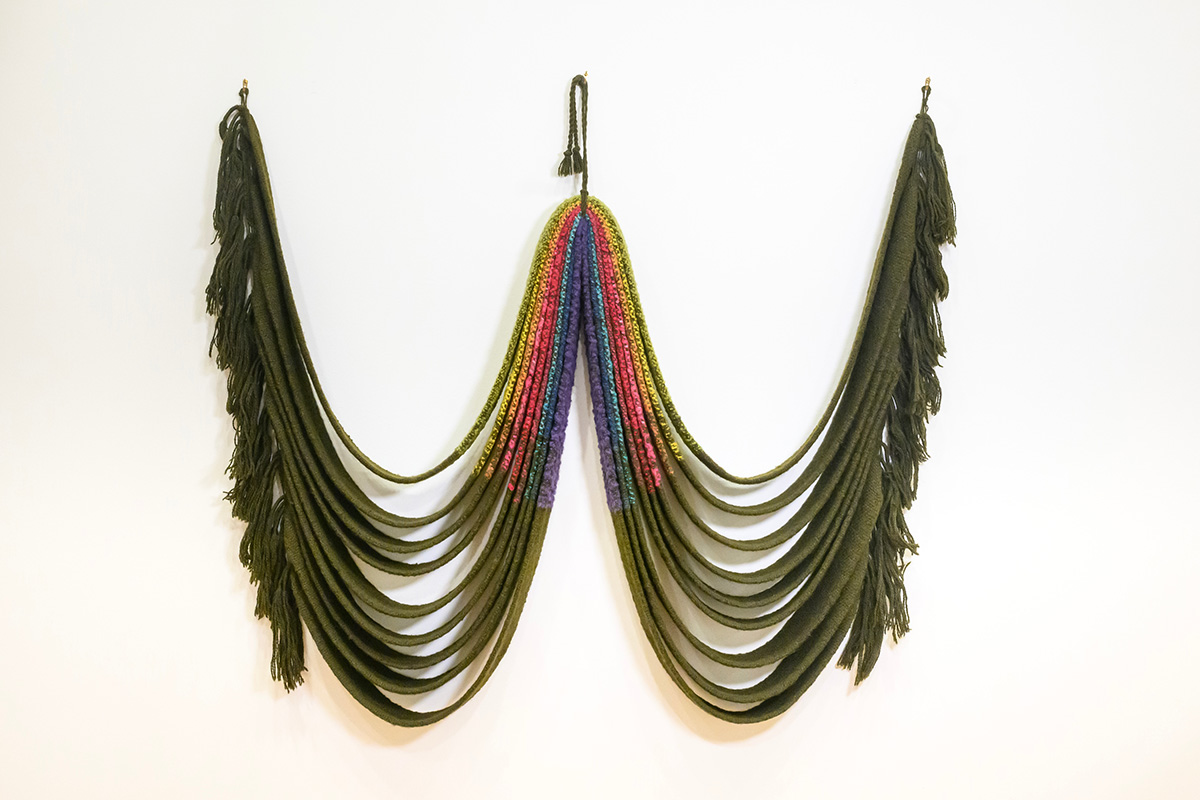 Photo of a woven olive-green wall hanging with draped curves.