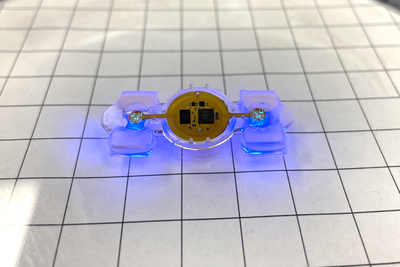 A photograph of an eBiobot prototype, lit with blue microLEDs.