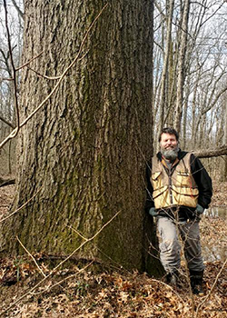 Evans stands next to a state champion pin oak tree in Union County, Illinois.