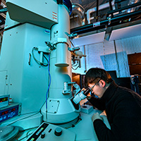 Graduate student seated at the tranmission electron microscope in Chen’s lab at U. of I.