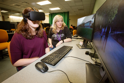 Photo of U. of I. computer science lecturer Anna Yershova and a student peering through a virtual reality headset.