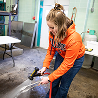 Cleanup and food safety, Jenna knows, are key to quality work as she power-washes her grilling tongs.