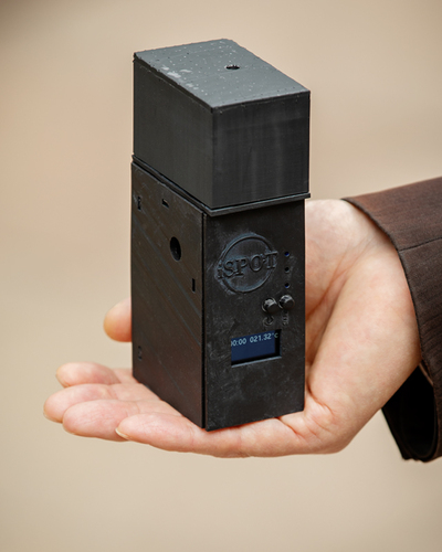 Photo of a hand holding a black rectangular testing device.