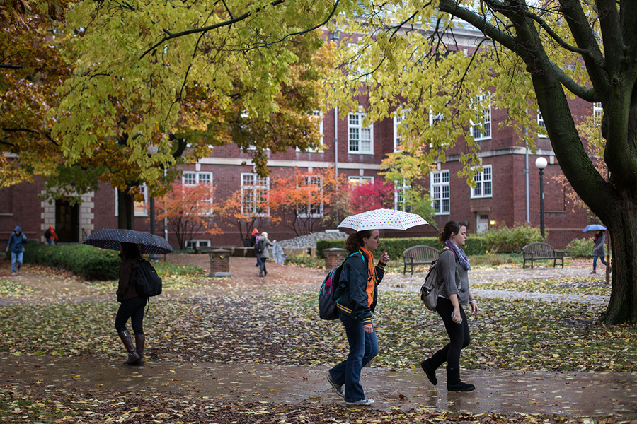 Students with umbrellas walking on sidewalks