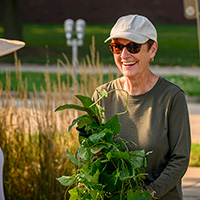 Photo of Gloria Rainer talking with a volunteer in the garden.