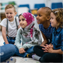 photo of diverse group of children sitting on the floor together in a classroom