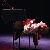 Photo of an actor lying across a chair with his feet up and his head back and mouth open, as though screaming.
