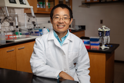 Dr. Leyi Wang in his lab, wearing his white veterinarian's coat.