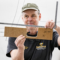 Photo of Douglas Brooks holding up a piece of wood and a T-square.