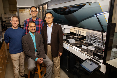 Scott Weisberg, left, professor Saurabh Sinha, seated, Mohammad (Sam) Hamedi Rad and professor Huimin Zhao have combined a fully automated robotic platform with artificial intelligence to develop a new way to manufacture chemicals.