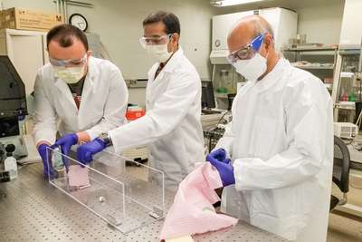 Mechanical science and engineering professor Taher Saif, right, and students Onur Aydin, left, and Bashar Emon test common household fabrics used to make face masks to help stop the spread of the coronavirus.