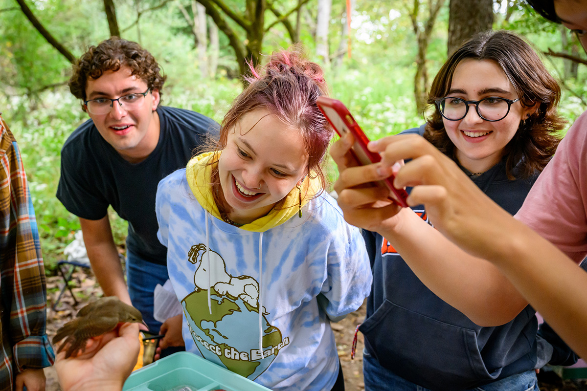 Student volunteers from the Wildlife Society’s U. of I. student chapter move in close to see a tiny yet spirited bird, the house wren, before it is released.