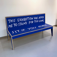 Image of a bright blue bench painted with the words,