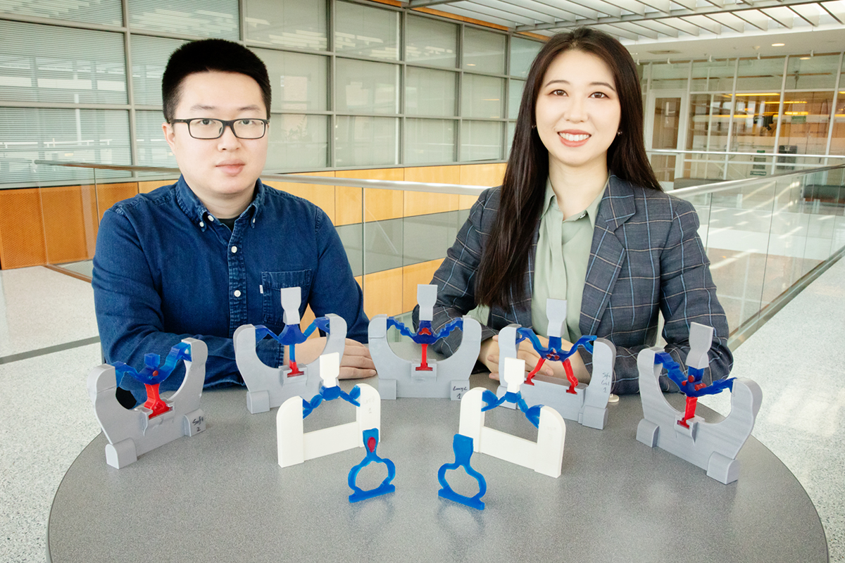 Researchers at a table with various models of new multimaterial devices.