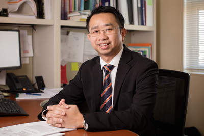 Social work professor Kevin Tan sitting at his desk in his office on the University of Illinois campus